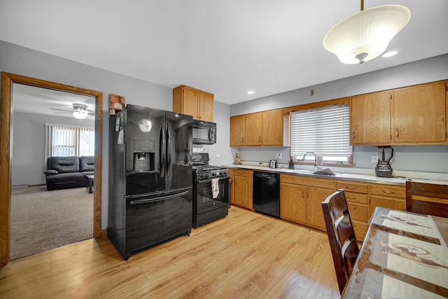 370 N Commonwealth Ave, Elgin, IL 60123 - kitchen featuring black appliances, a sink, light countertops, light wood-style floors, and brown cabinetry
