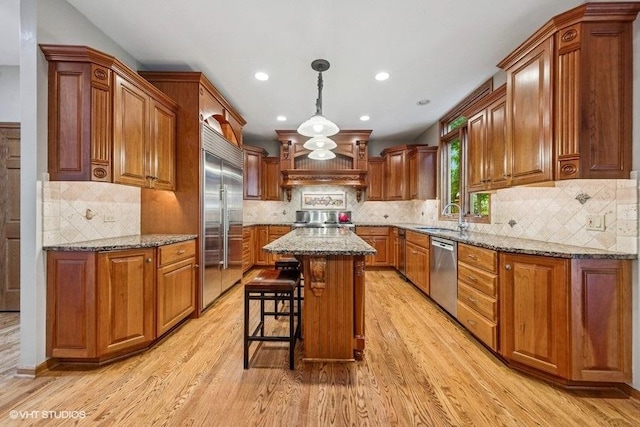 3104 Royal Fox Dr, Saint Charles, IL 60174 - kitchen featuring stainless steel appliances, brown cabinetry, light wood-style floors, recessed lighting, and light stone countertops
