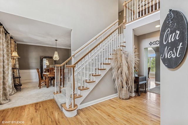 9520 Nicklaus Ln, Crystal Lake, IL 60014 - stairway featuring wood finished floors, ornamental molding, a towering ceiling, a chandelier, and a wainscoted wall