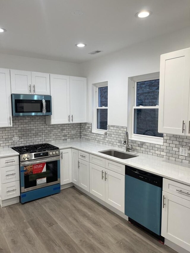 6141 S Eberhart Ave, Chicago, IL 60637 - kitchen with appliances with stainless steel finishes, a sink, white cabinetry, light countertops, and backsplash