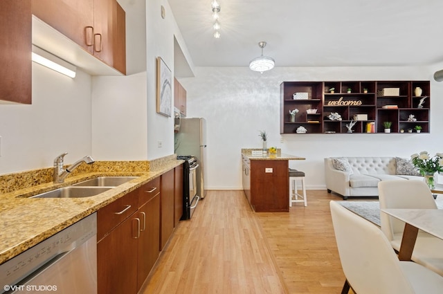 4537 S Drexel Blvd Unit 106, Chicago, IL 60653 - kitchen with stainless steel appliances, light wood-type flooring, a kitchen bar, light stone counters, and brown cabinets