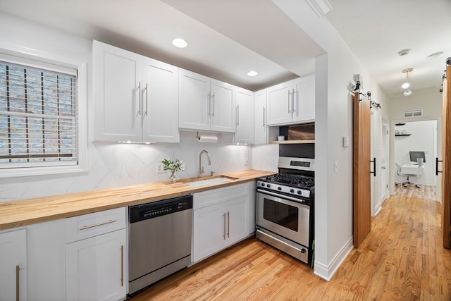 1443 N Mohawk St Unit 1, Chicago, IL 60610 - kitchen with appliances with stainless steel finishes, butcher block countertops, light wood finished floors, decorative backsplash, and recessed lighting