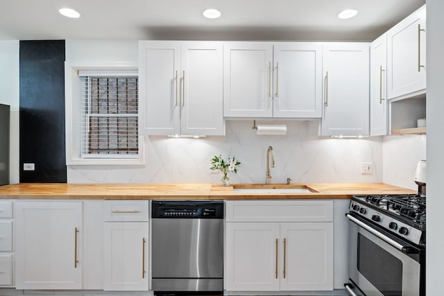 1443 N Mohawk St Unit 1, Chicago, IL 60610 - kitchen with butcher block counters, stainless steel appliances, white cabinets, backsplash, and recessed lighting