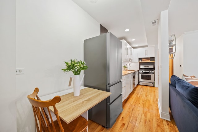 1443 N Mohawk St Unit 1, Chicago, IL 60610 - kitchen with stainless steel appliances, white cabinetry, light wood-style flooring, light countertops, and recessed lighting