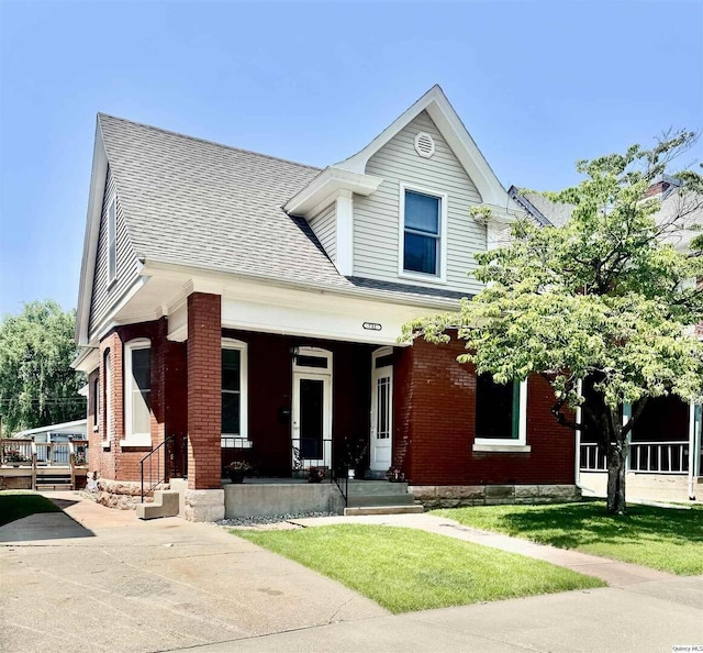 732 S 13th, Quincy, IL 62301 - view of front of house featuring a porch, brick siding, a front yard, and roof with shingles