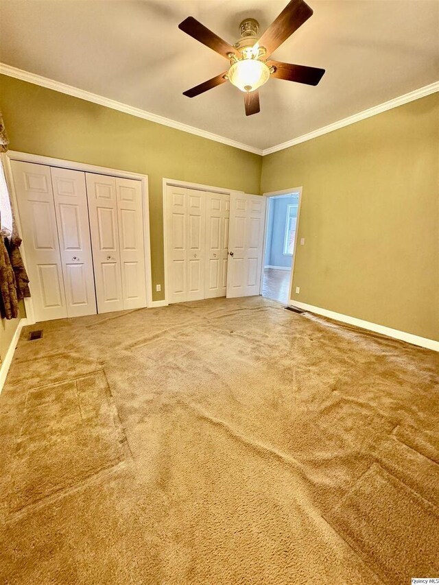 732 S 13th, Quincy, IL 62301 - unfurnished bedroom featuring two closets, carpet, ornamental molding, baseboards, and a ceiling fan
