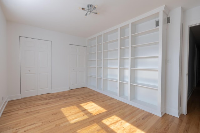 3145 Hillside Ln, Darien, IL 60561 - unfurnished bedroom featuring wood finished floors and two closets