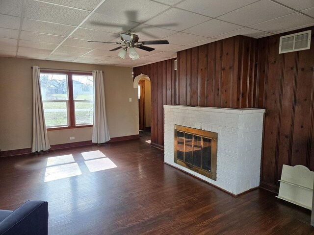 16517 Plainview Dr, Markham, IL 60428 - unfurnished living room featuring arched walkways, a paneled ceiling, wooden walls, ceiling fan, and dark wood-type flooring