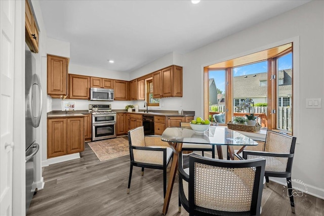 957 Whittington Dr, Geneva, IL 60134 - kitchen with stainless steel appliances, brown cabinetry, wood finished floors, recessed lighting, and dark countertops