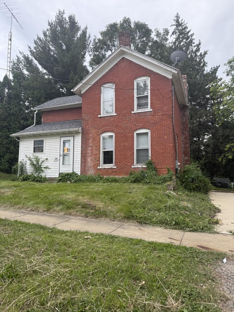 509 W Chestnut St, Freeport, IL 61032 - view of front facade featuring a chimney, a front yard, and brick siding