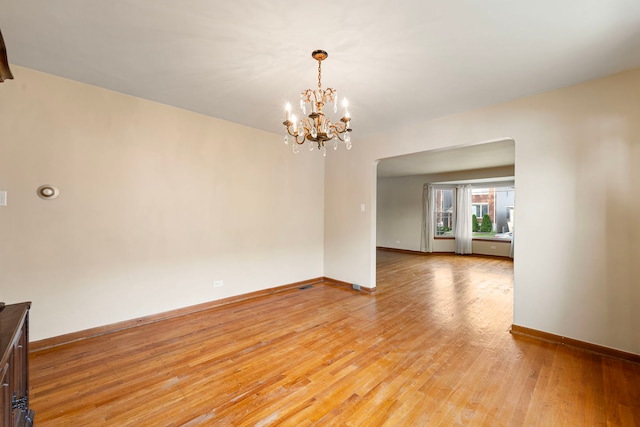 2728 N Neva Ave, Chicago, IL 60707 - empty room with light wood-style flooring, a chandelier, and arched walkways