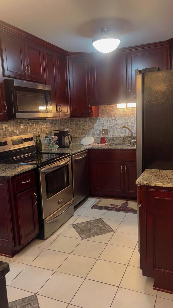 3427 Vollmer Rd Unit 108, Flossmoor, IL 60422 - kitchen featuring stainless steel appliances, reddish brown cabinets, a sink, backsplash, and light stone counters
