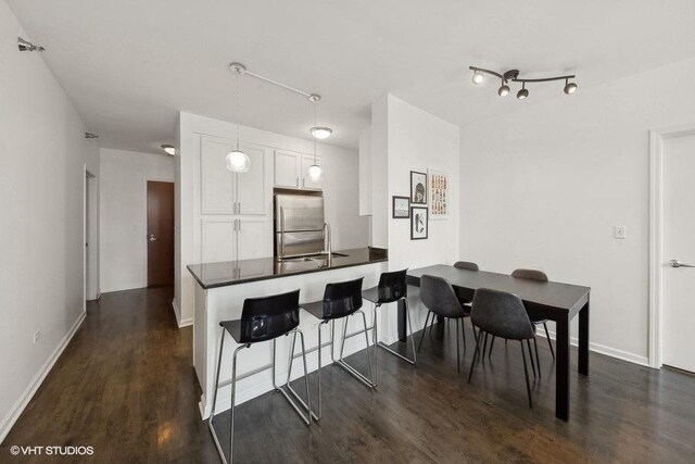 1255 S State St Unit 911, Chicago, IL 60605 - kitchen featuring stainless steel refrigerator, white cabinetry, dark countertops, dark wood finished floors, and a kitchen bar
