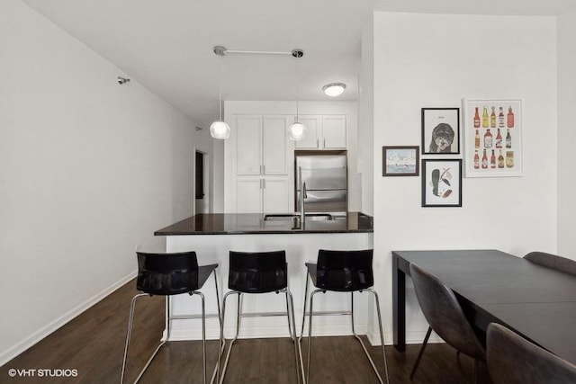 1255 S State St Unit 911, Chicago, IL 60605 - kitchen with a kitchen bar, dark countertops, white cabinets, stainless steel fridge, and dark wood-style floors