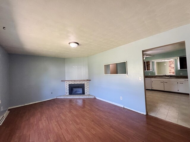 310 N 3rd Ave, Chenoa, IL 61726 - unfurnished living room with wood finished floors, a sink, a fireplace, and baseboards