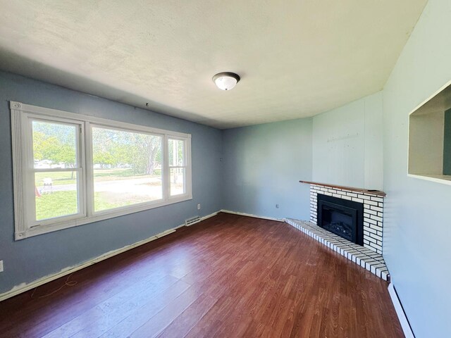 310 N 3rd Ave, Chenoa, IL 61726 - unfurnished living room featuring wood finished floors, a brick fireplace, and baseboards