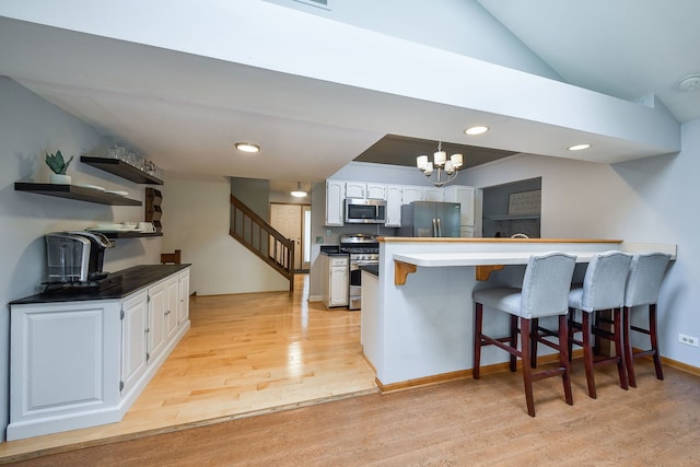 27W108 Walnut Dr, Winfield, IL 60190 - kitchen featuring appliances with stainless steel finishes, white cabinets, light wood finished floors, a peninsula, and a kitchen breakfast bar