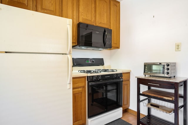 7416 Van Buren Ave, Hammond, IN 46324 - kitchen featuring freestanding refrigerator, black microwave, gas stove, light countertops, and brown cabinetry