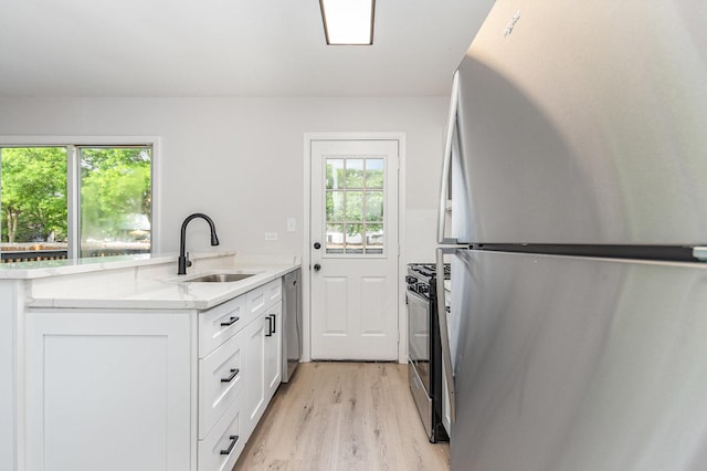 7490 Filmore Ave, Hanover Park, IL 60133 - kitchen with stainless steel appliances, light wood-style floors, white cabinets, light stone counters, and a peninsula