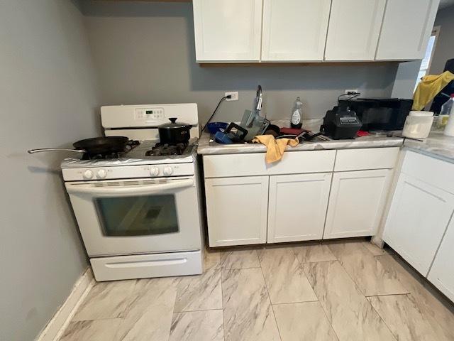 8205 S Houston Ave, Chicago, IL 60617 - kitchen featuring white range with gas stovetop, white cabinets, light countertops, and light marble finish floors