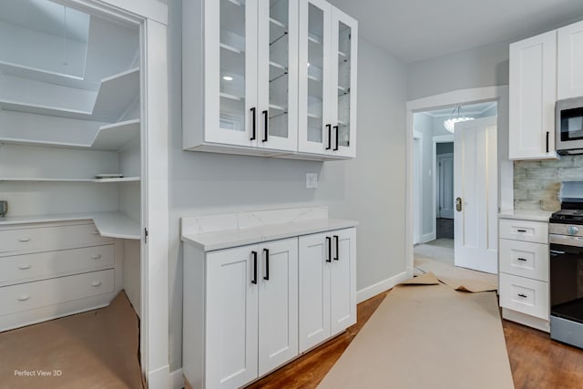 5448 N Lieb Ave, Chicago, IL 60630 - kitchen featuring stainless steel appliances, white cabinetry, glass insert cabinets, and backsplash
