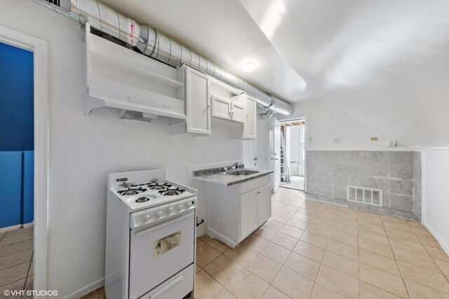2625 S Drake Ave, Chicago, IL 60623 - kitchen with white range with gas stovetop, light tile patterned flooring, open shelves, white cabinets, and light countertops