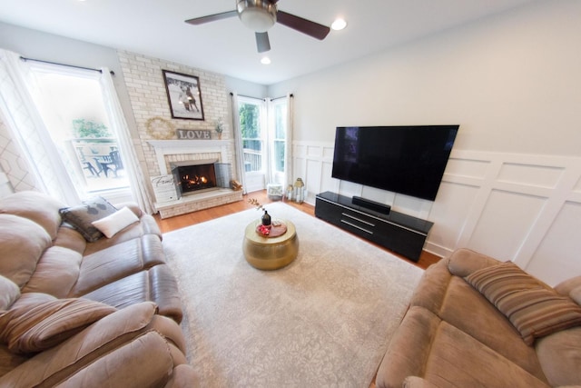 1034 Idaho St, Carol Stream, IL 60188 - living area with a ceiling fan, wood finished floors, a decorative wall, a brick fireplace, and a wainscoted wall