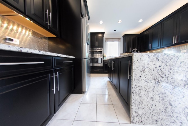 1034 Idaho St, Carol Stream, IL 60188 - kitchen with dark cabinets, light tile patterned flooring, decorative backsplash, double oven, and light stone counters