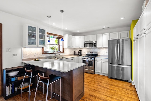 4413 N Malden St Unit 2S, Chicago, IL 60640 - kitchen with appliances with stainless steel finishes, a peninsula, glass insert cabinets, a breakfast bar, and tasteful backsplash