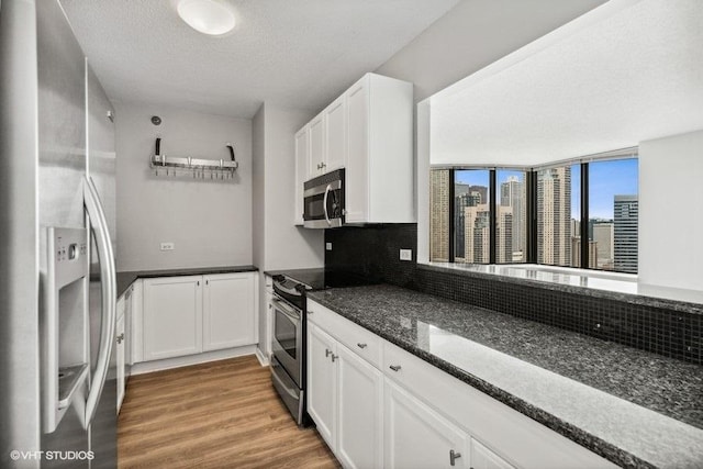 400 N La Salle Dr Unit 3002, Chicago, IL 60654 - kitchen featuring stainless steel appliances, light wood-style floors, tasteful backsplash, white cabinets, and a textured ceiling