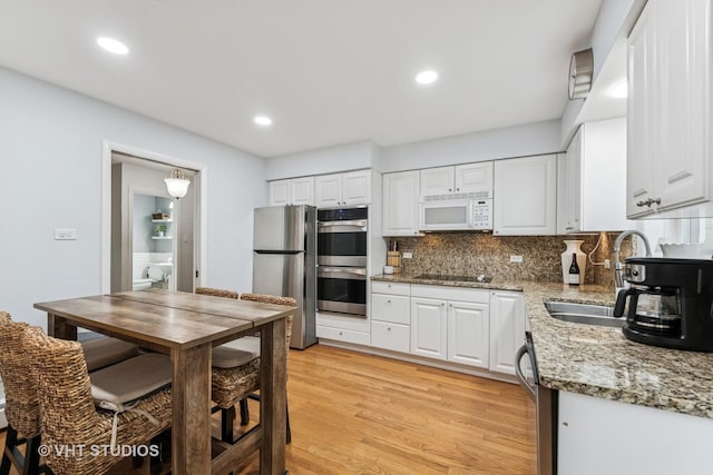504 S Spring Ave, La Grange, IL 60525 - kitchen featuring stainless steel appliances, white cabinetry, light wood finished floors, decorative backsplash, and light stone counters