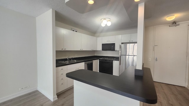 405 N Wabash Ave Unit 102, Chicago, IL 60611 - kitchen featuring black appliances, a sink, dark countertops, light wood-style flooring, and white cabinetry