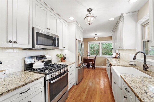 728 S Hillside Ave, Elmhurst, IL 60126 - kitchen featuring stainless steel appliances, white cabinets, light wood-style floors, a sink, and baseboards