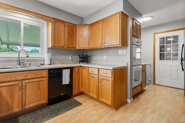 1716 Park Haven Dr, Champaign, IL 61820 - kitchen featuring black dishwasher, a sink, double oven, light wood-style floors, and light countertops