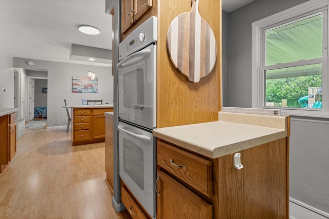 1716 Park Haven Dr, Champaign, IL 61820 - kitchen featuring brown cabinets, light countertops, light wood-type flooring, baseboards, and double oven