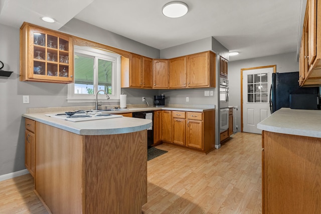 1716 Park Haven Dr, Champaign, IL 61820 - kitchen featuring black appliances, light wood-style floors, a peninsula, light countertops, and a sink