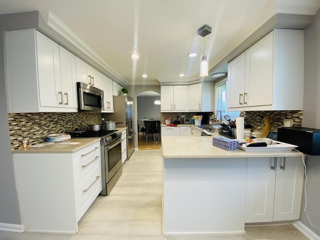 1106 Westfield Ln, Schaumburg, IL 60193 - kitchen featuring appliances with stainless steel finishes, a peninsula, crown molding, backsplash, and white cabinetry