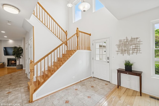 11 Litchfield Ct, Lake In The Hills, IL 60156 - foyer entrance featuring stairway, a lit fireplace, a high ceiling, and wood finished floors