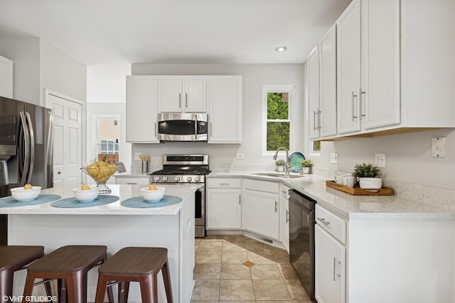 11 Litchfield Ct, Lake In The Hills, IL 60156 - kitchen featuring appliances with stainless steel finishes, a kitchen bar, white cabinetry, light countertops, and light tile patterned floors