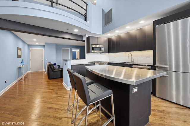 616 W Fulton St Unit 703, Chicago, IL 60661 - kitchen with stainless steel countertops, appliances with stainless steel finishes, a breakfast bar, a kitchen island, and light wood-style floors