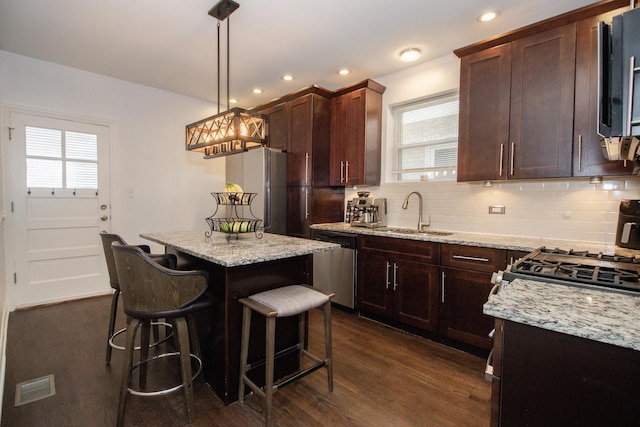 5236 W Nelson St, Chicago, IL 60641 - kitchen featuring appliances with stainless steel finishes, dark wood finished floors, backsplash, a breakfast bar, and light stone counters
