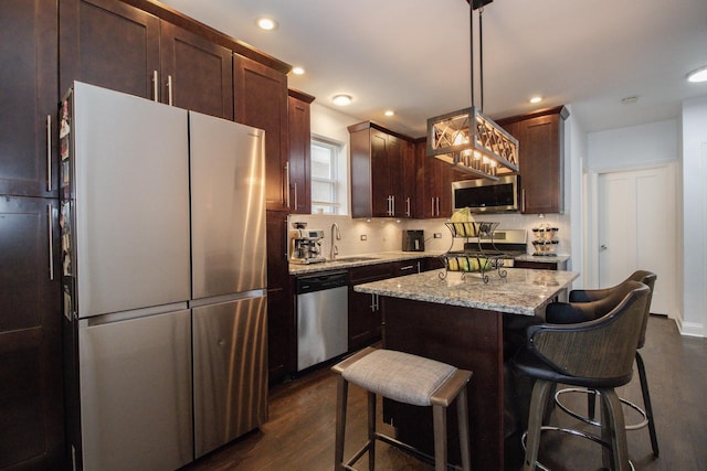 5236 W Nelson St, Chicago, IL 60641 - kitchen with stainless steel appliances, light stone counters, a breakfast bar area, a center island, and hanging light fixtures
