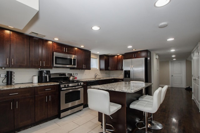 5236 W Nelson St, Chicago, IL 60641 - kitchen with stainless steel appliances, a breakfast bar, backsplash, a center island, and light stone countertops