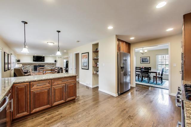 613 Michelline Ln, Northbrook, IL 60062 - kitchen featuring appliances with stainless steel finishes, open floor plan, wood finished floors, light stone countertops, and hanging light fixtures