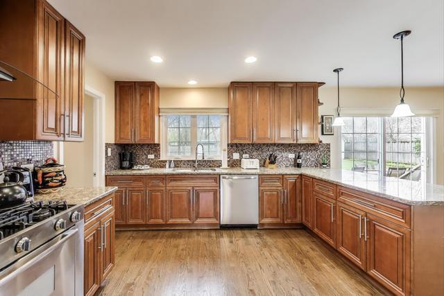 613 Michelline Ln, Northbrook, IL 60062 - kitchen with appliances with stainless steel finishes, a sink, brown cabinetry, light stone counters, and recessed lighting