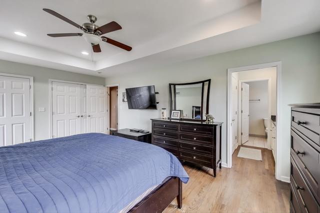 613 Michelline Ln, Northbrook, IL 60062 - bedroom featuring a tray ceiling, light wood-style floors, recessed lighting, multiple closets, and a ceiling fan