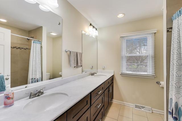 613 Michelline Ln, Northbrook, IL 60062 - full bathroom featuring toilet, double vanity, tile patterned flooring, baseboards, and a shower with shower curtain