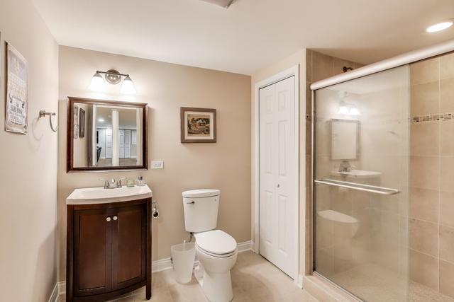 613 Michelline Ln, Northbrook, IL 60062 - full bathroom featuring toilet, a stall shower, vanity, and baseboards
