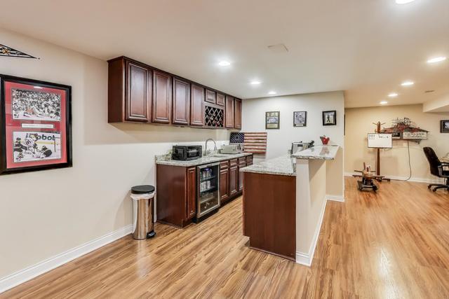 613 Michelline Ln, Northbrook, IL 60062 - kitchen with beverage cooler, light wood-type flooring, recessed lighting, dark brown cabinetry, and baseboards