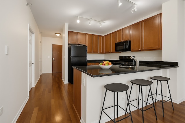 1255 S State St Unit 1704, Chicago, IL 60605 - kitchen with black appliances, a peninsula, dark wood-style flooring, and brown cabinetry